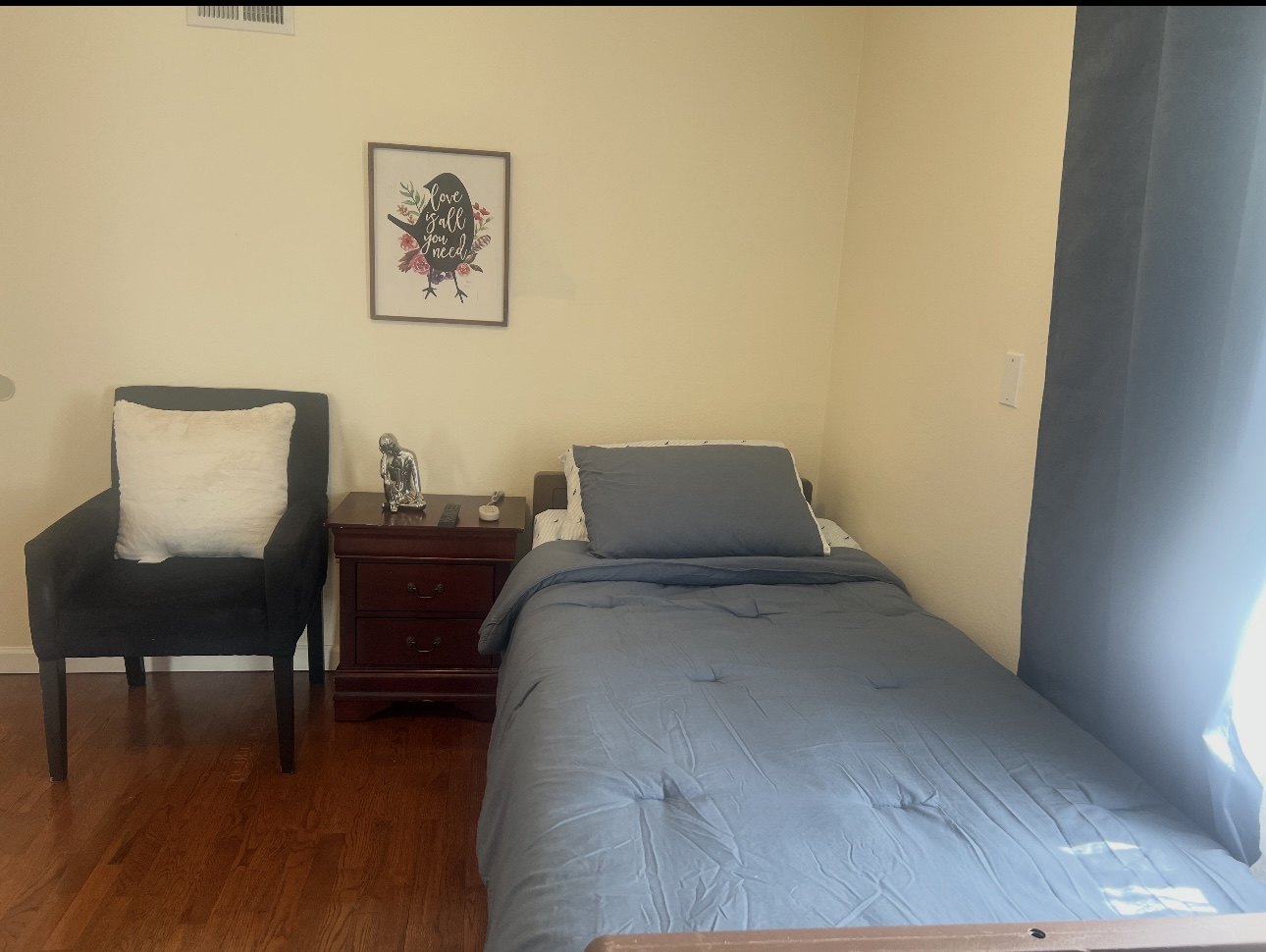 Resident bedroom with blue bedding and bedside chair
