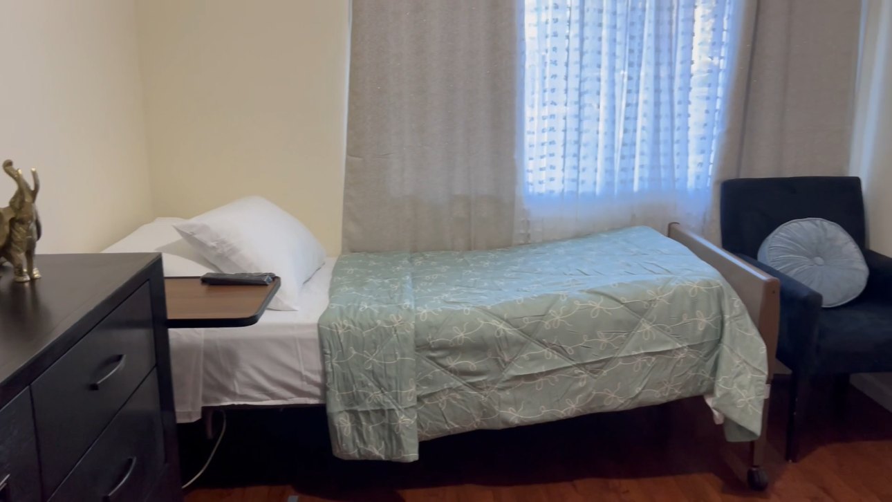 Resident bedroom with pale green bedding and chair